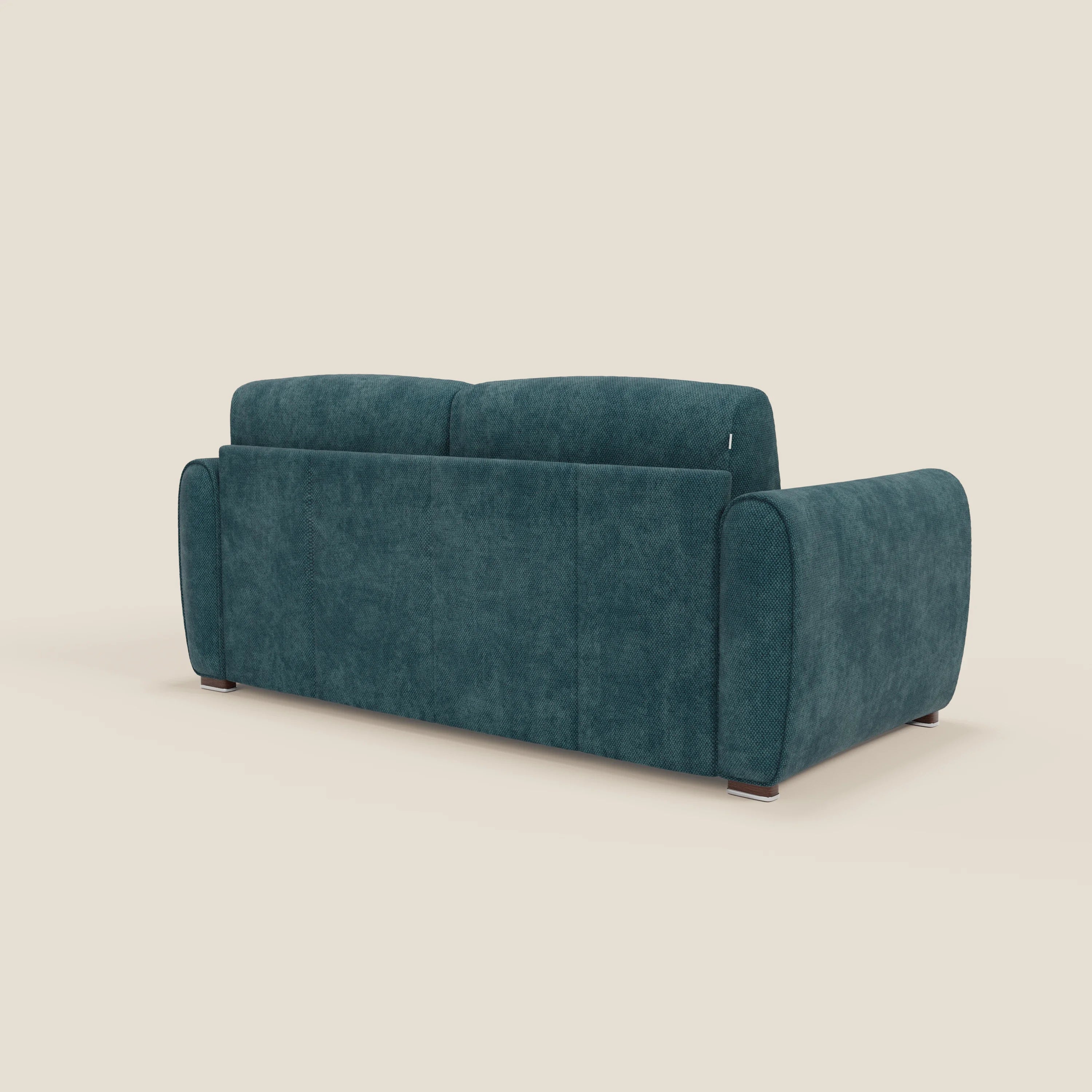 Il divano letto moderno Kaleo di Divani.Store, in tessuto impermeabile T26 petrolio, è caratterizzato da un profilo basso, braccioli arrotondati, sottili piedini in legno e un materasso H17 cm. Presentato in posizione obliqua su uno sfondo beige semplice per un look morbido e minimalista.