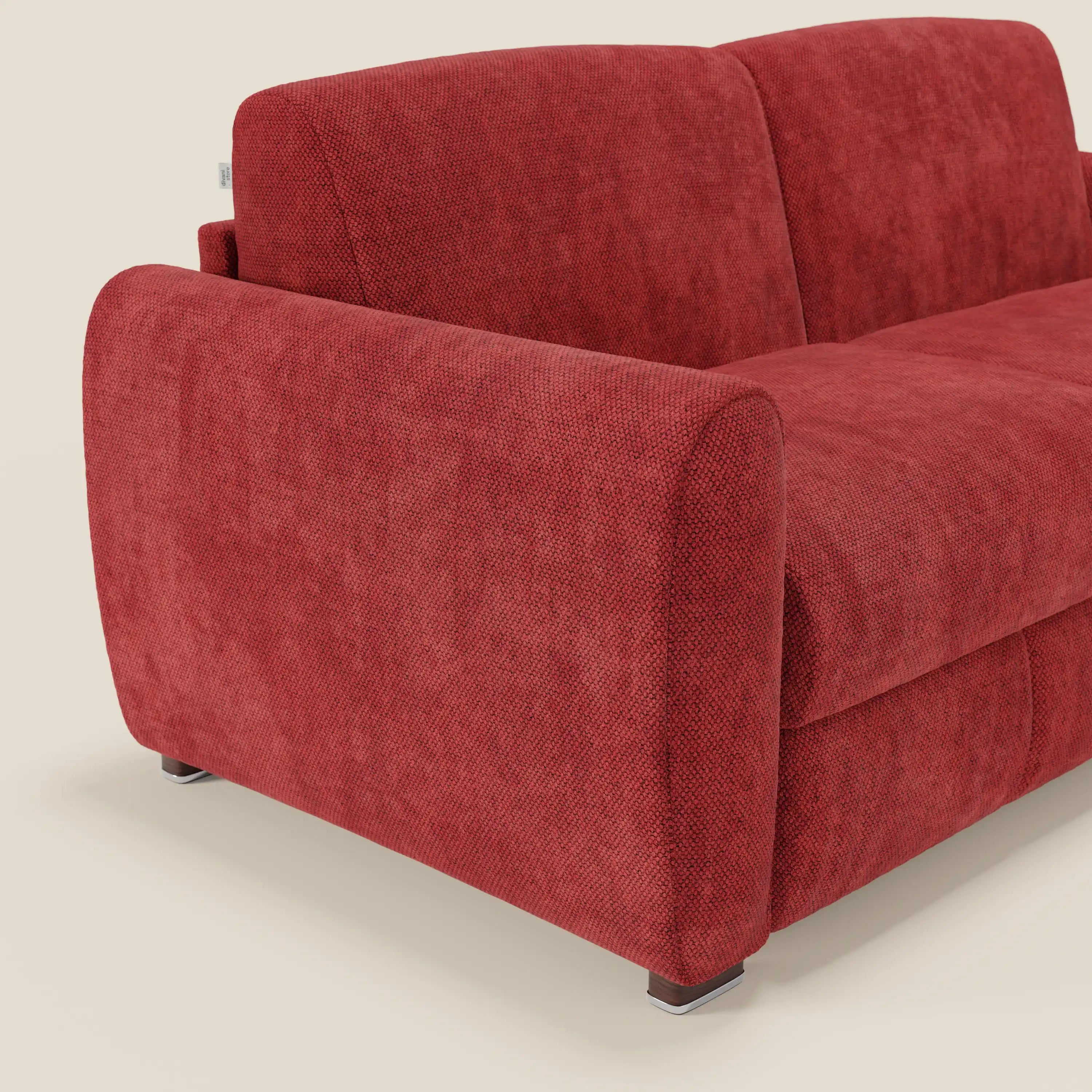 Primo piano del divano letto moderno Kaleo di Divani.Store in vivace tessuto impermeabile rosso T26, con spessi braccioli e corte gambe argentate. Solo una parte del lato sinistro e dello schienale del divano sono visibili su uno sfondo beige chiaro.