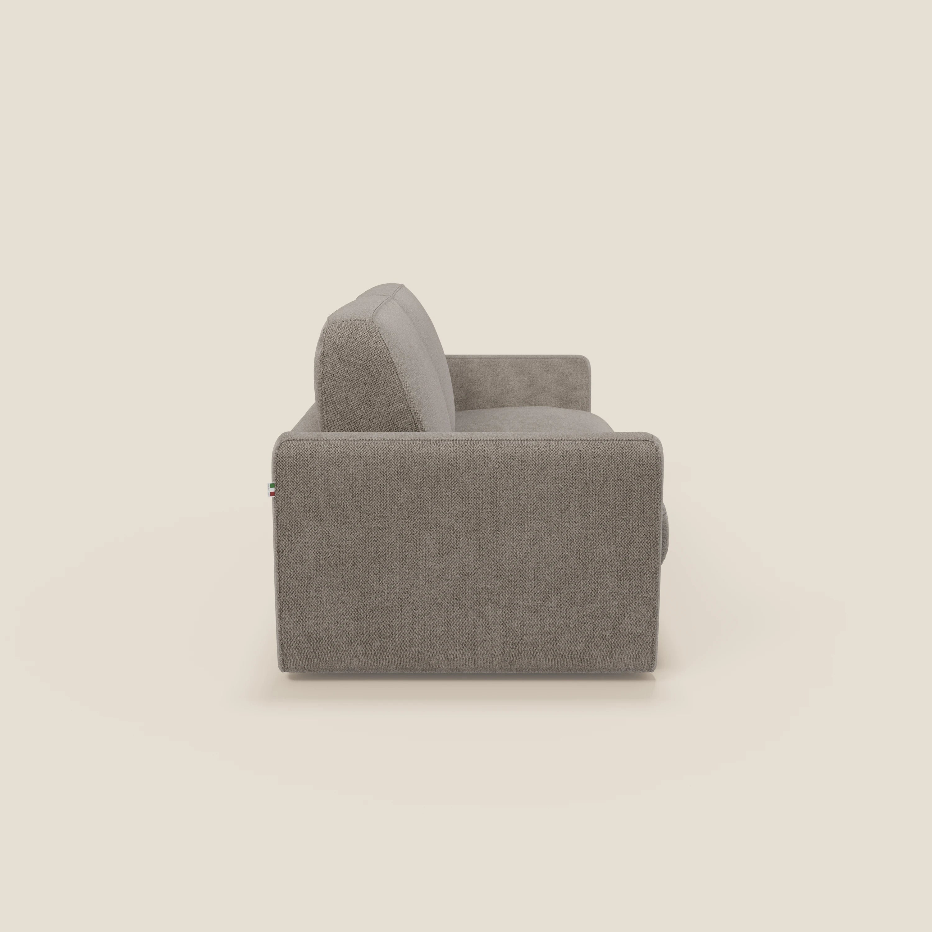 Vista laterale del divano letto sfoderabile Leonida di Divani.Store in tessuto smacchiabile T23 talpa, caratterizzato da braccioli squadrati, schienale imbottito, materasso H18 cm e vano portacuscini su sfondo beige.