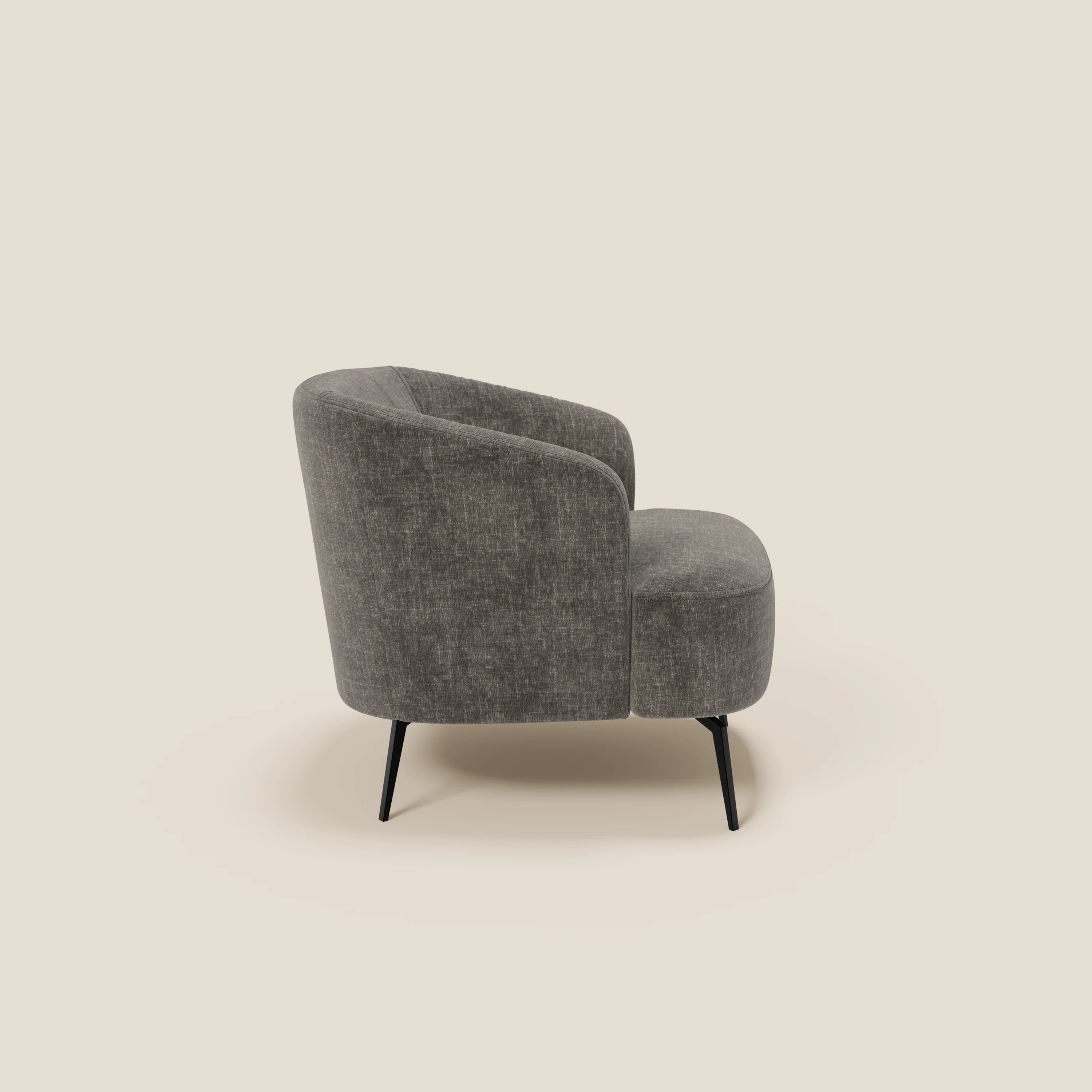 La poltroncina Renoa dall'eleganza moderna di Divani.Store è caratterizzata da un tessuto antracite T24 antimacchia grigio, da uno schienale e da una seduta arrotondati, da sottili gambe angolate in metallo nero e da un'atmosfera confortevole su uno sfondo beige chiaro con ombre morbide.