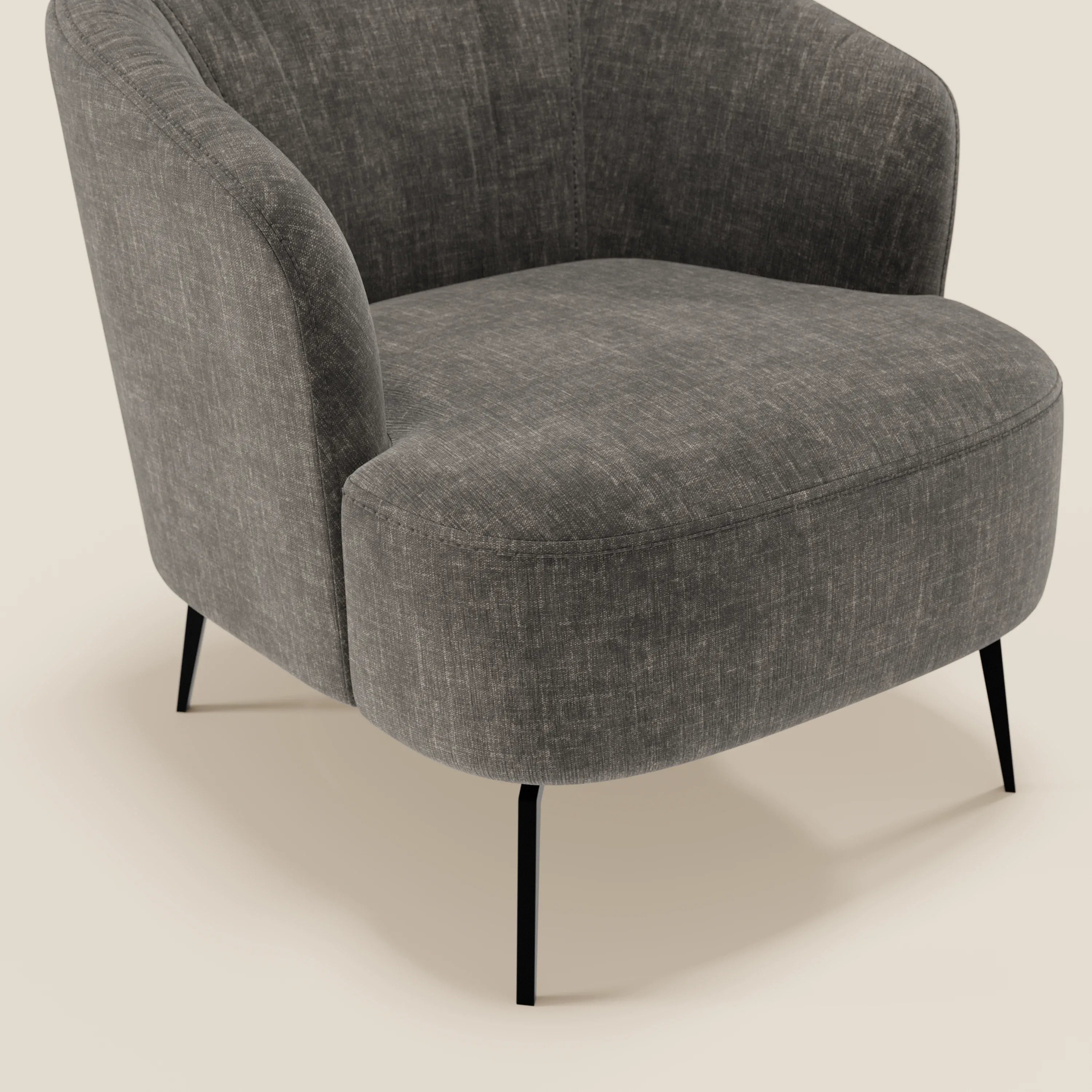 La poltroncina Renoa di Divani.Store vanta un'eleganza moderna grazie al tessuto antracite antimacchia T24, allo schienale arrotondato, al morbido cuscino della seduta e alle sottili gambe in metallo nero. Solo una parte della sedia appare su uno sfondo beige chiaro.