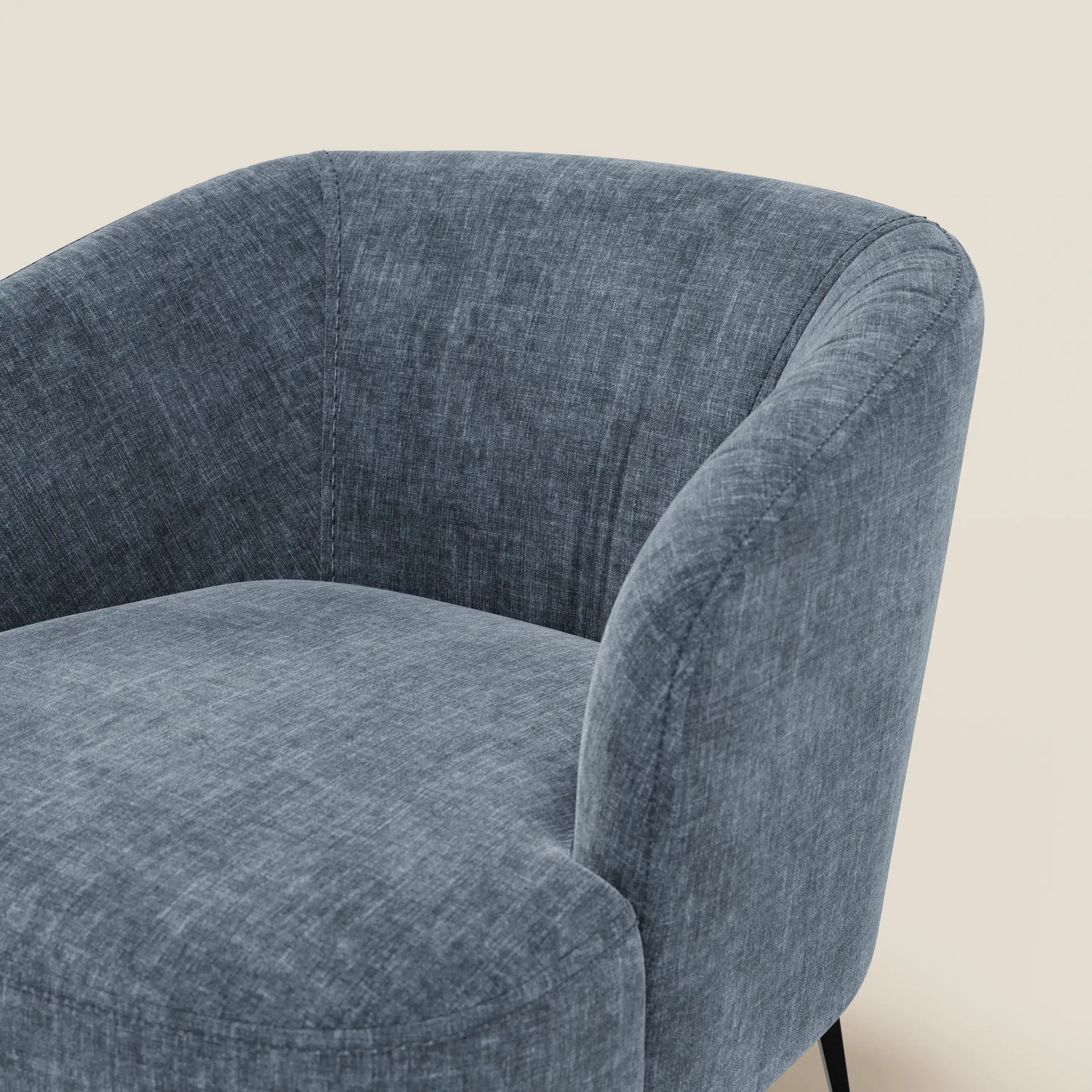 La poltroncina Renoa dall'eleganza moderna in tessuto smacchiabile T24 blu ardesia di Divani.Store, con schienale e braccioli curvi, è mostrata su sfondo beige chiaro. Sono visibili solo la parte superiore e parte della seduta.