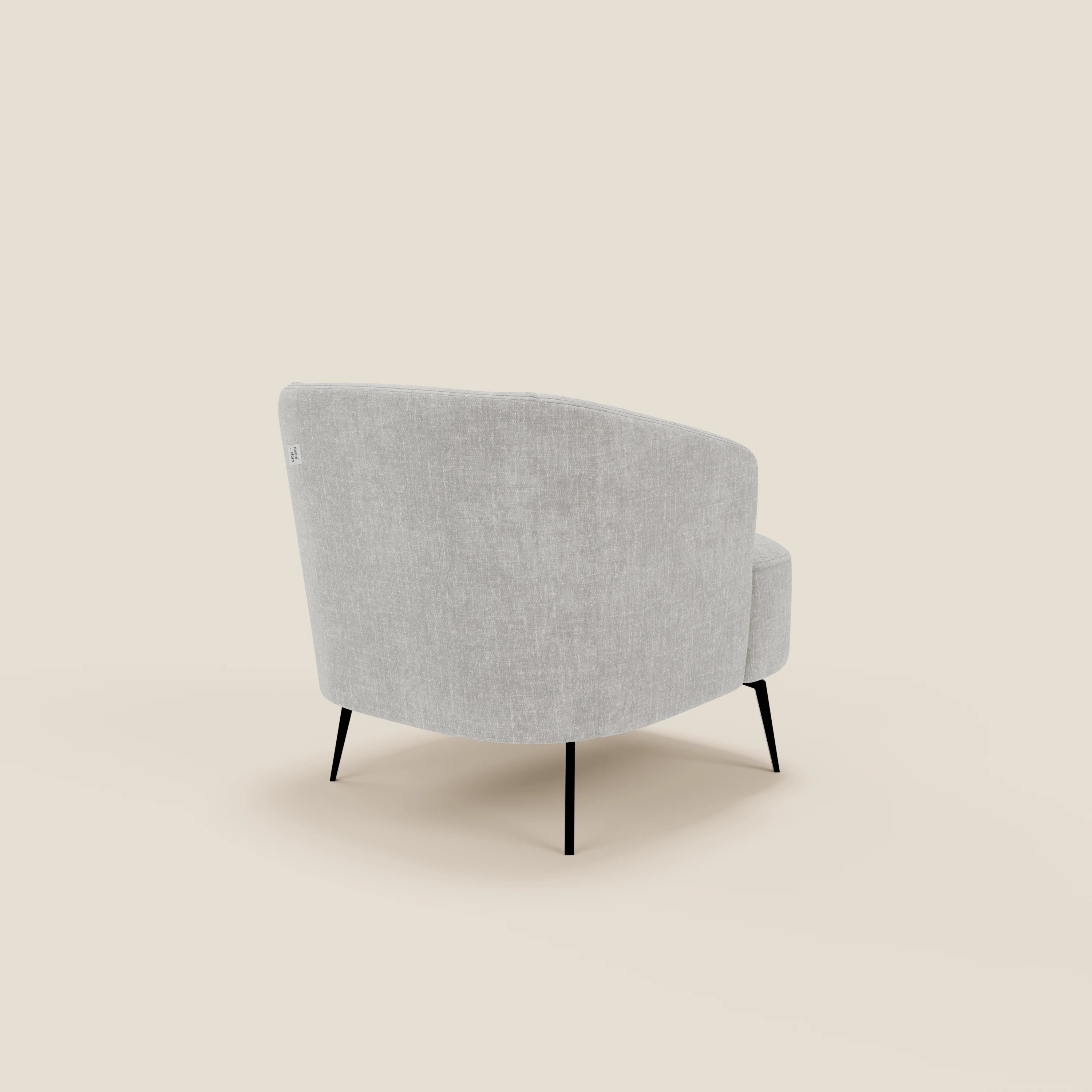 La poltroncina Renoa dall'eleganza moderna in tessuto smacchiabile T24 grigio di Divani.Store viene mostrata dal retro, mettendo in evidenza la sua forma curva, il comfort avvolgente e le sottili gambe in metallo nero su uno sfondo bianco sporco.