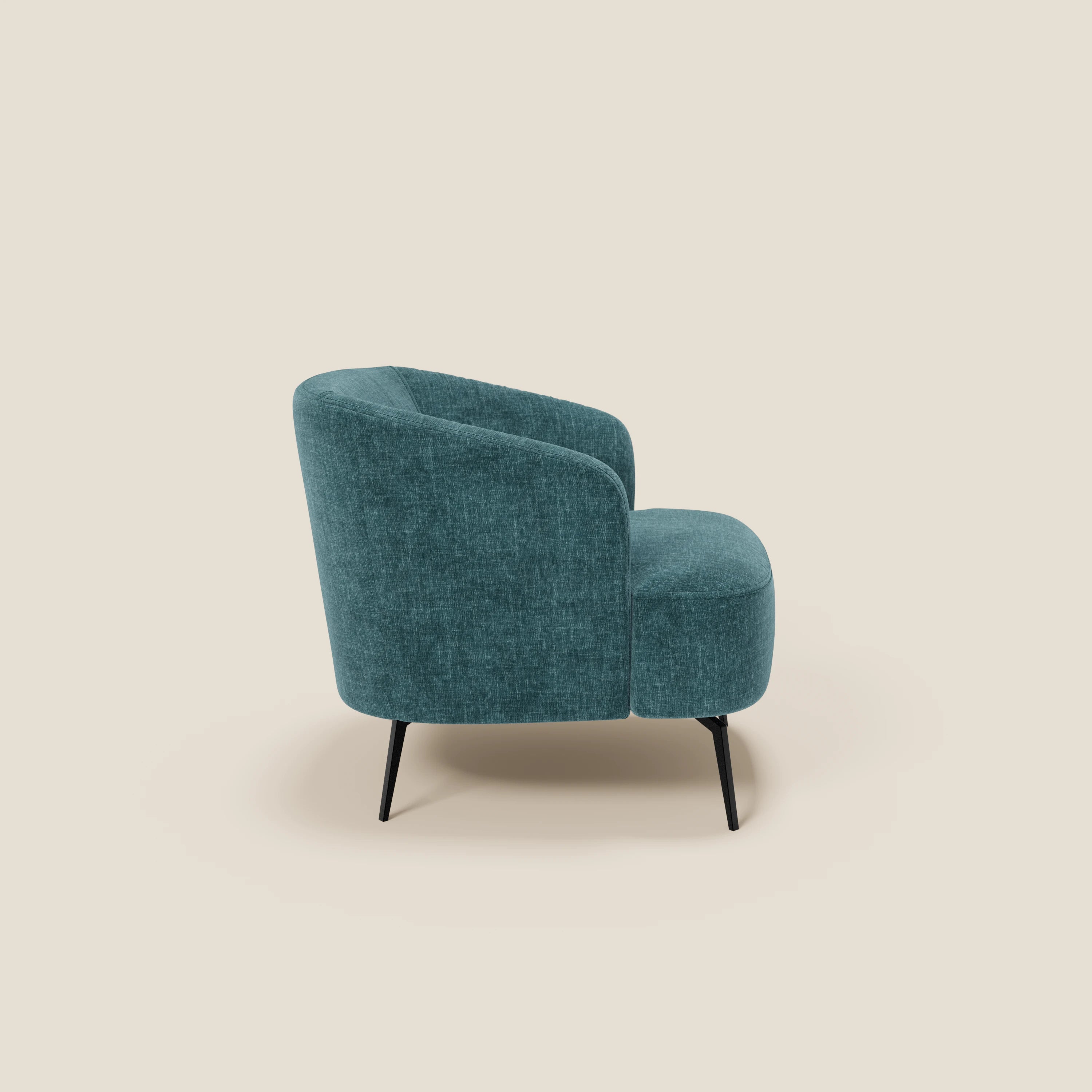 La poltroncina Renoa di Divani.Store, in tessuto smacchiabile T24 petrolio, sfoggia eleganza moderna con schienale curvo, gambe sottili in metallo nero e design avvolgente che spicca su fondo beige.