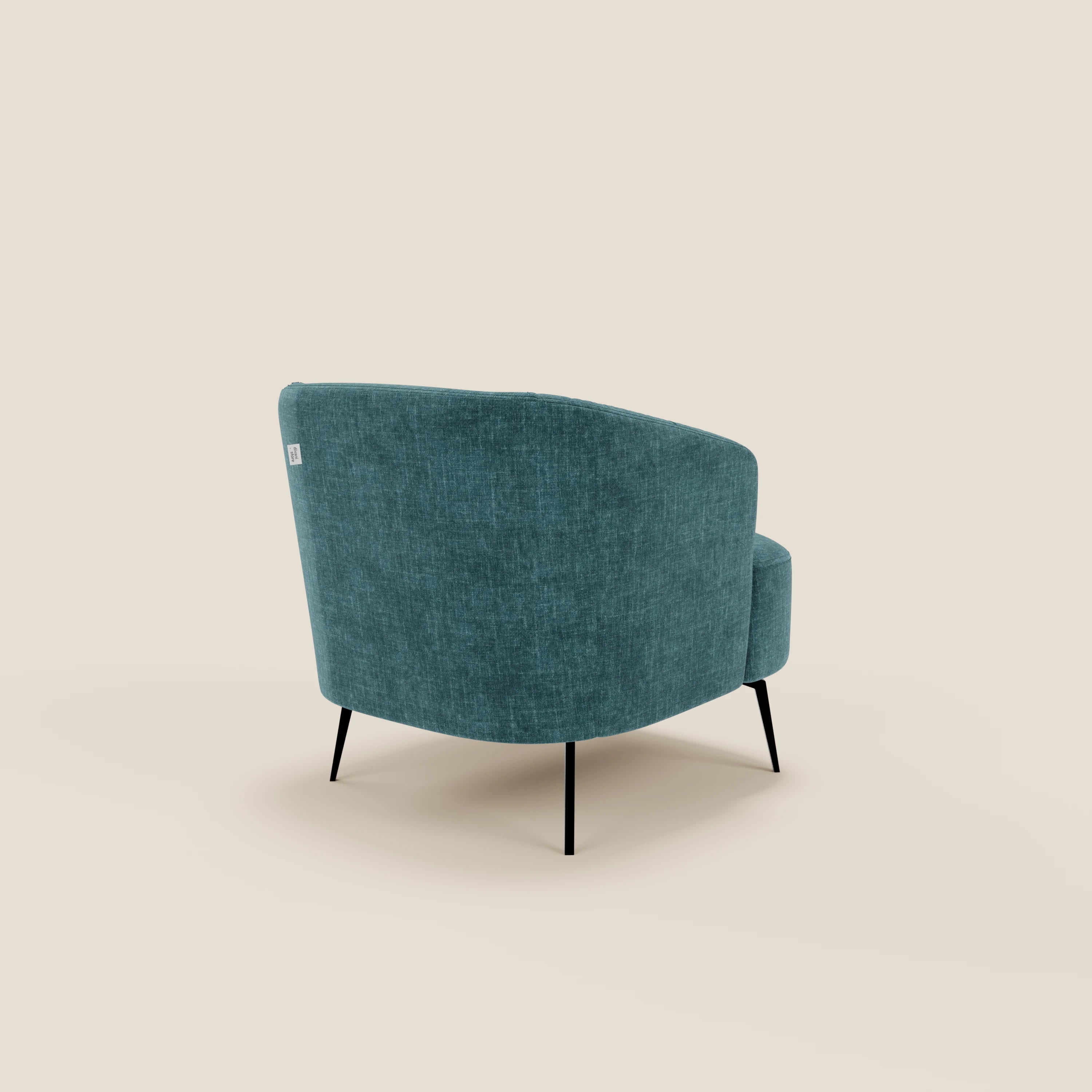 La poltroncina Renoa dall'eleganza moderna in tessuto smacchiabile T24 petrolio di Divani.Store è mostrata dal retro in posizione angolata e mette in evidenza le sottili gambe in metallo nero, lo schienale curvo e il tessuto morbido su uno sfondo beige moderno.
