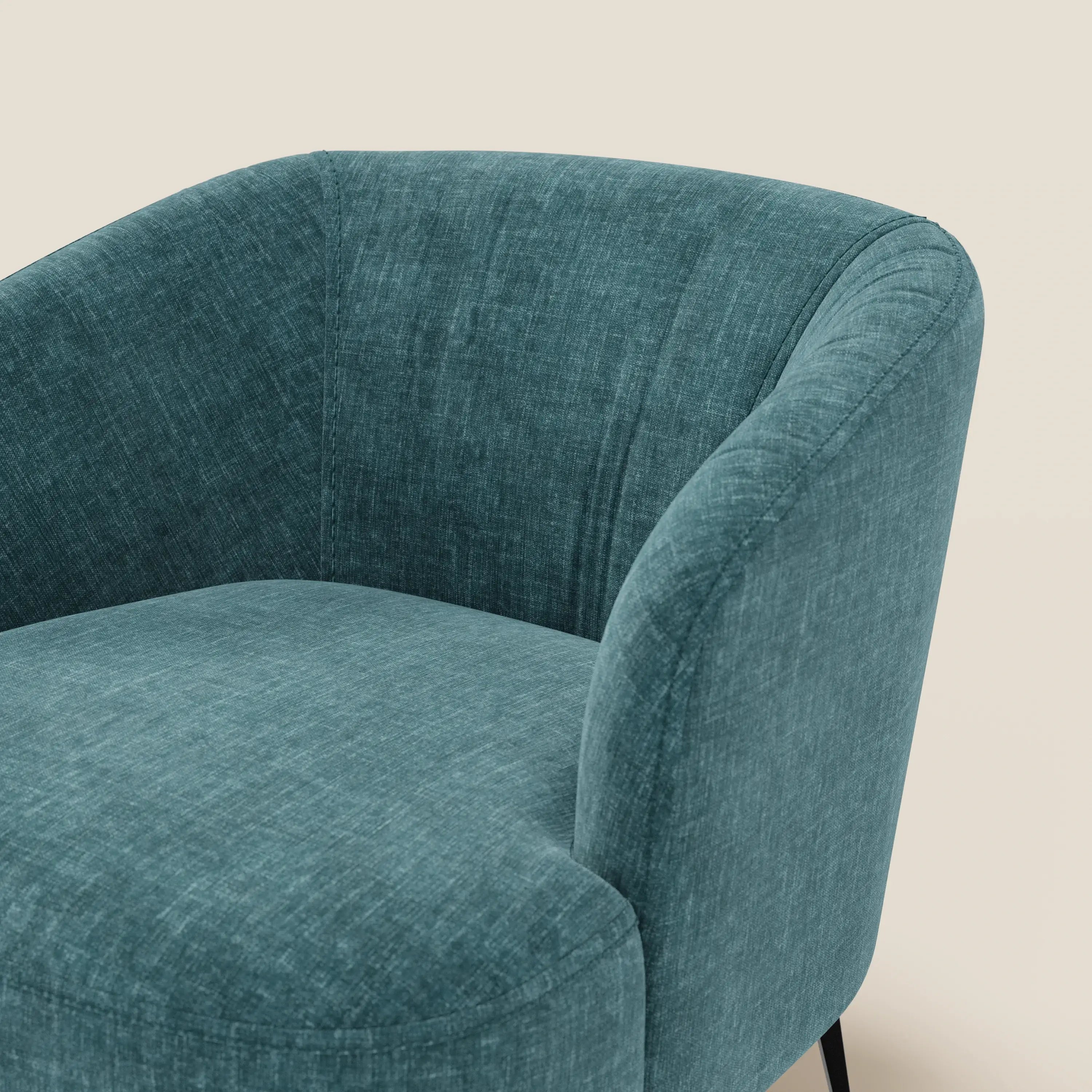 Primo piano della poltroncina Renoa di Divani.Store, caratterizzata da tessuto smacchiabile T24 petrolio, eleganza moderna con schienale arrotondato, morbida imbottitura avvolgente e sottili gambe in metallo nero su sfondo chiaro.