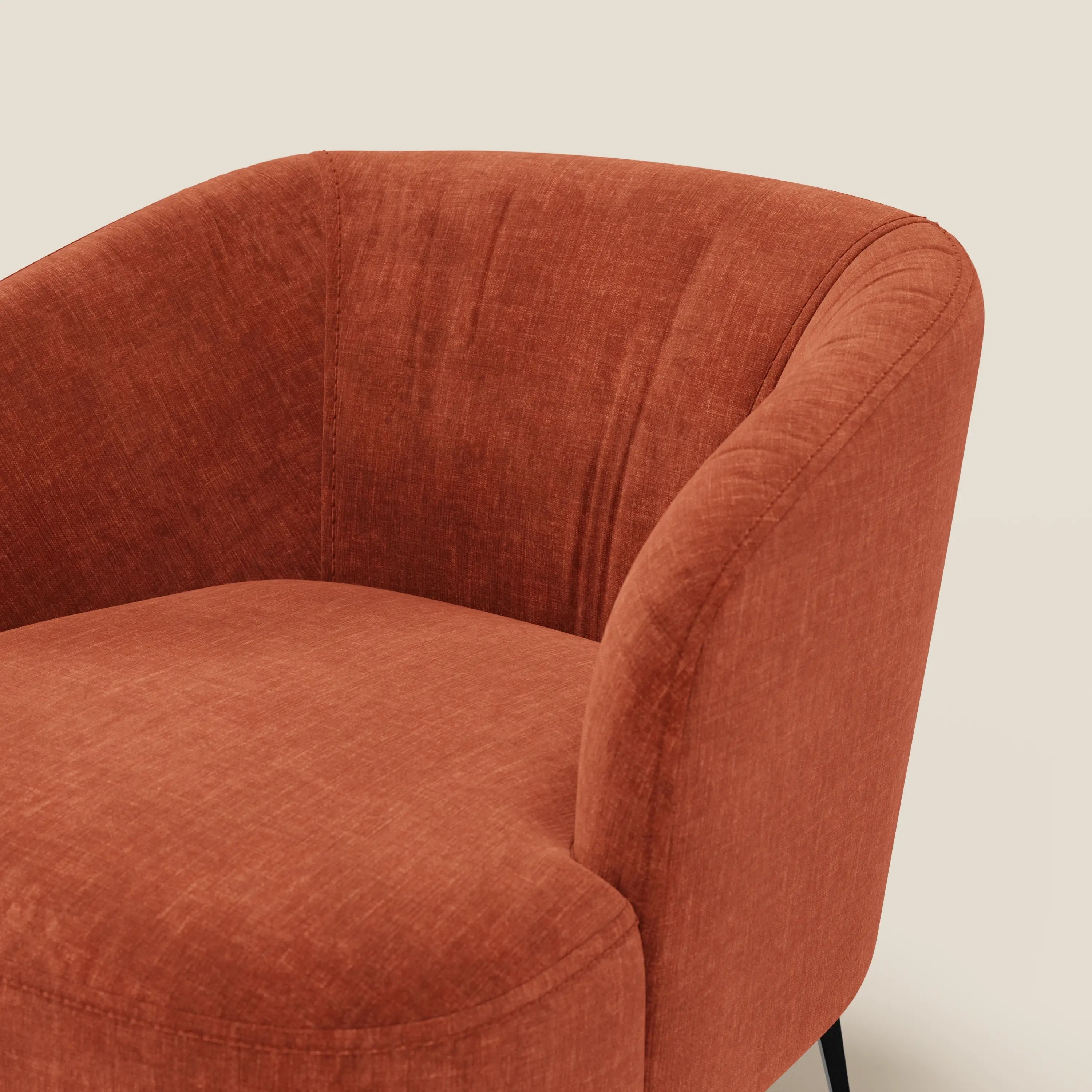 Primo piano della poltroncina Renoa di Divani.Store, caratterizzata da tessuto smacchiabile T24, schienale arrotondato, seduta imbottita e gambe affusolate nere. Il design moderno e l'aspetto morbido e vellutato risaltano su uno sfondo beige chiaro.