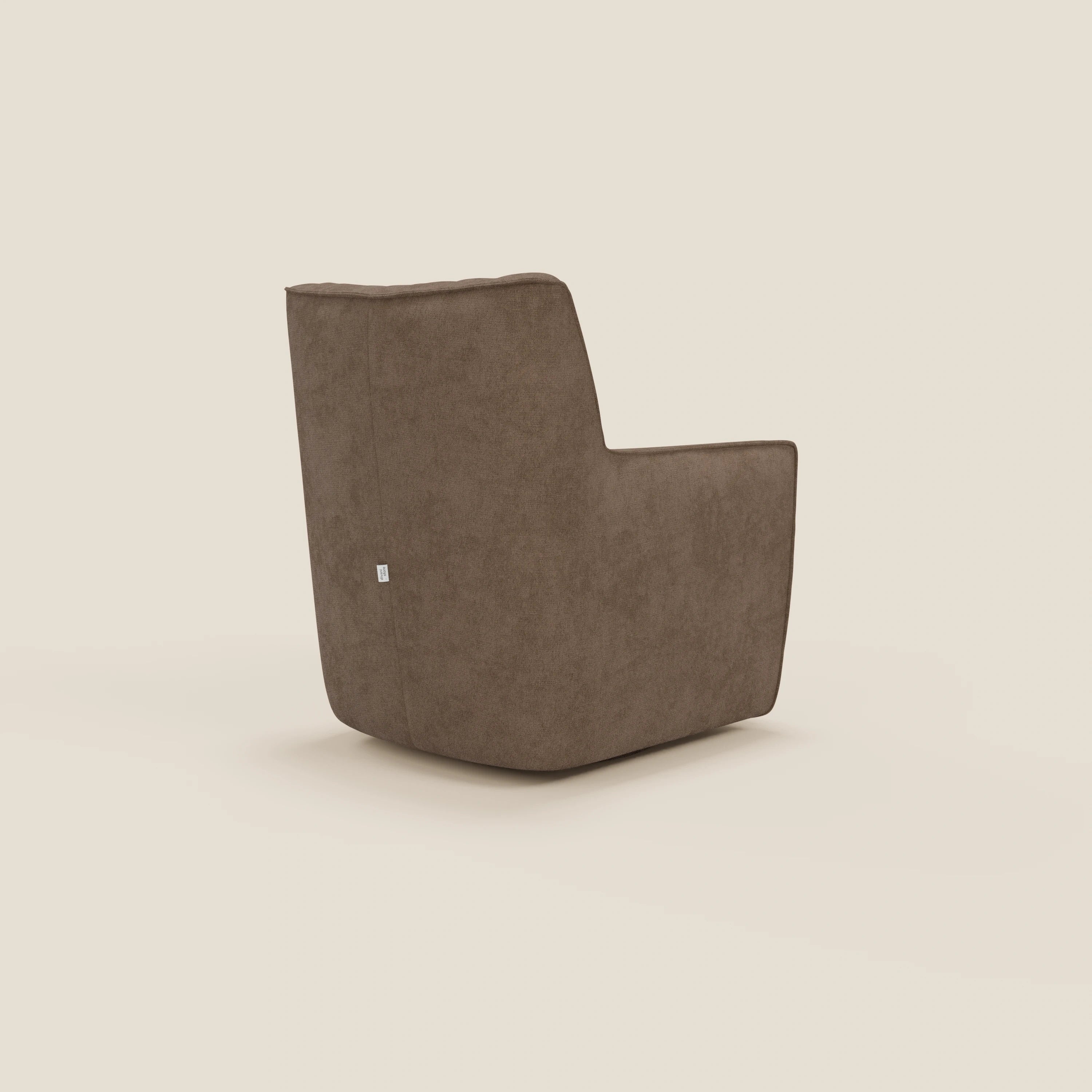 La poltrona girevole Tulla in tessuto impermeabile T02 marrone di Divani.Store è esposta in posizione angolata e mostra il suo design squadrato e minimalista, lo schienale alto e la piccola etichetta in tessuto, su uno sfondo beige.