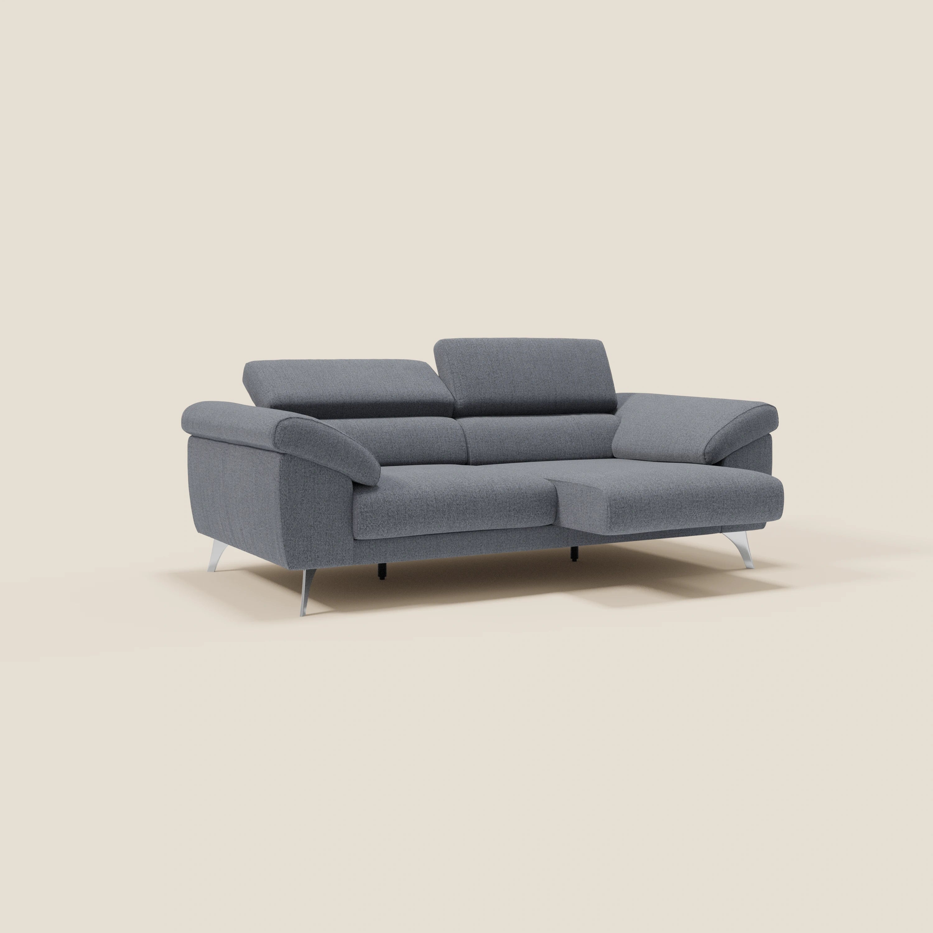 Un divano Donatello con sedute allungabili, braccioli contenitore e poggiatesta reclinabili in tessuto smacchiabile T23 blu grafite di Divani.Store è ambientato su sfondo beige, con chaise a destra e design contemporaneo per il massimo comfort.