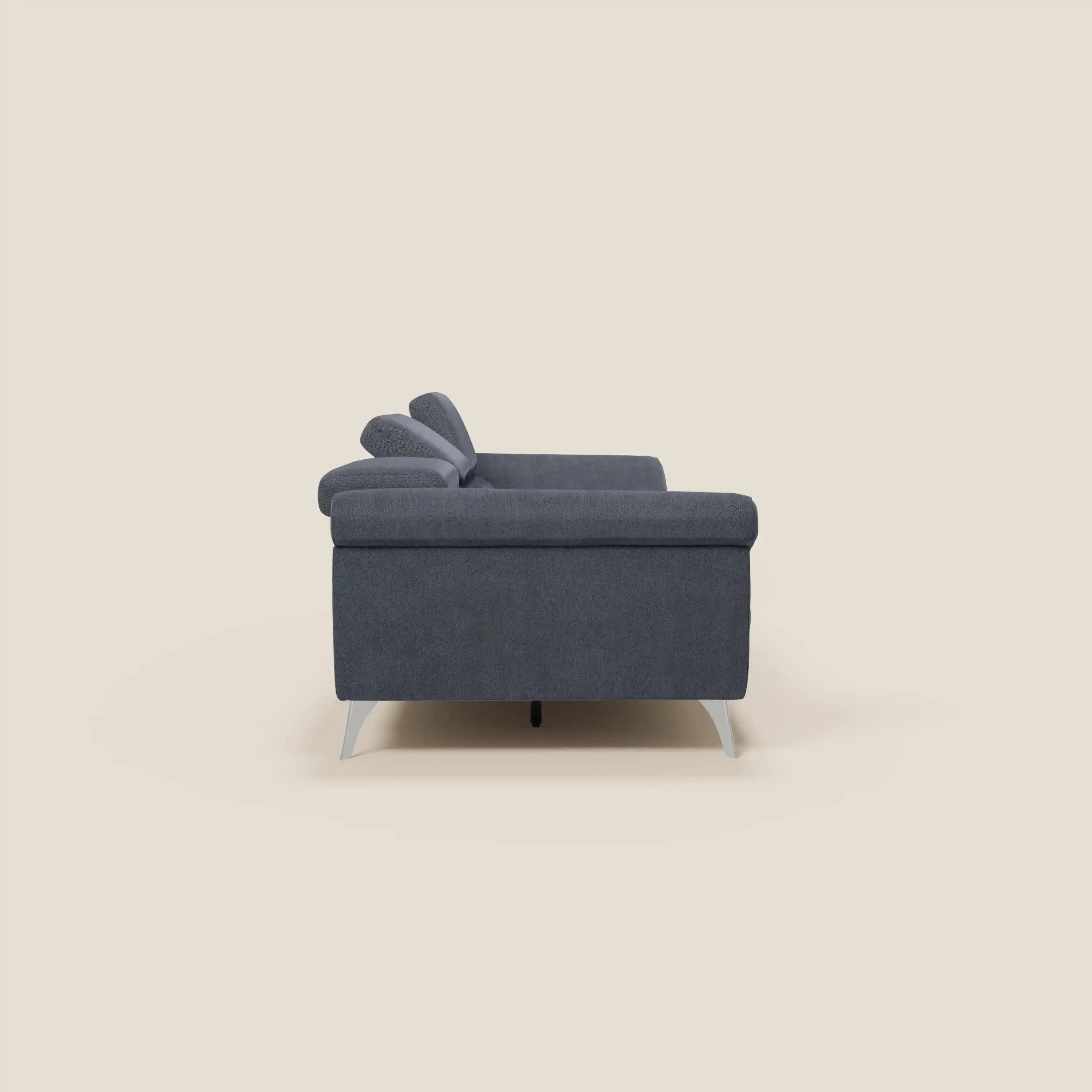 Il divano Donatello con 3 sedute allungabili di Divani.Store in tessuto smacchiabile T23 blu ardesia è mostrato lateralmente su sfondo beige, con linee pulite, braccioli contenitore e poggiatesta reclinabili per un look moderno.