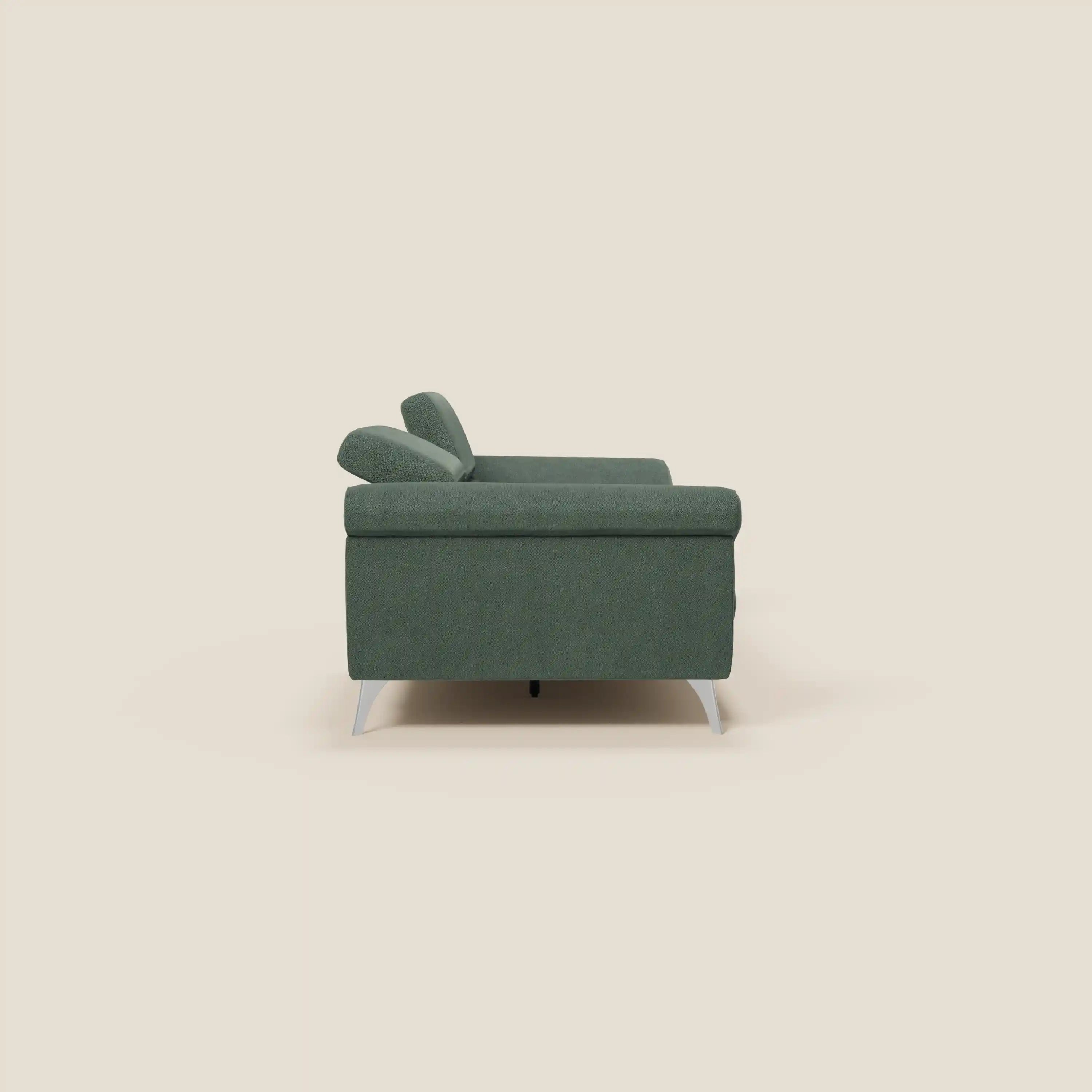 Il divano Donatello di Divani.Store, presentato in tessuto antimacchia T23 verde, è caratterizzato da sedute allungabili, braccioli contenitori e poggiatesta reclinabili. Visto di lato su uno sfondo beige, ha linee squadrate e uno stile moderno e minimalista.