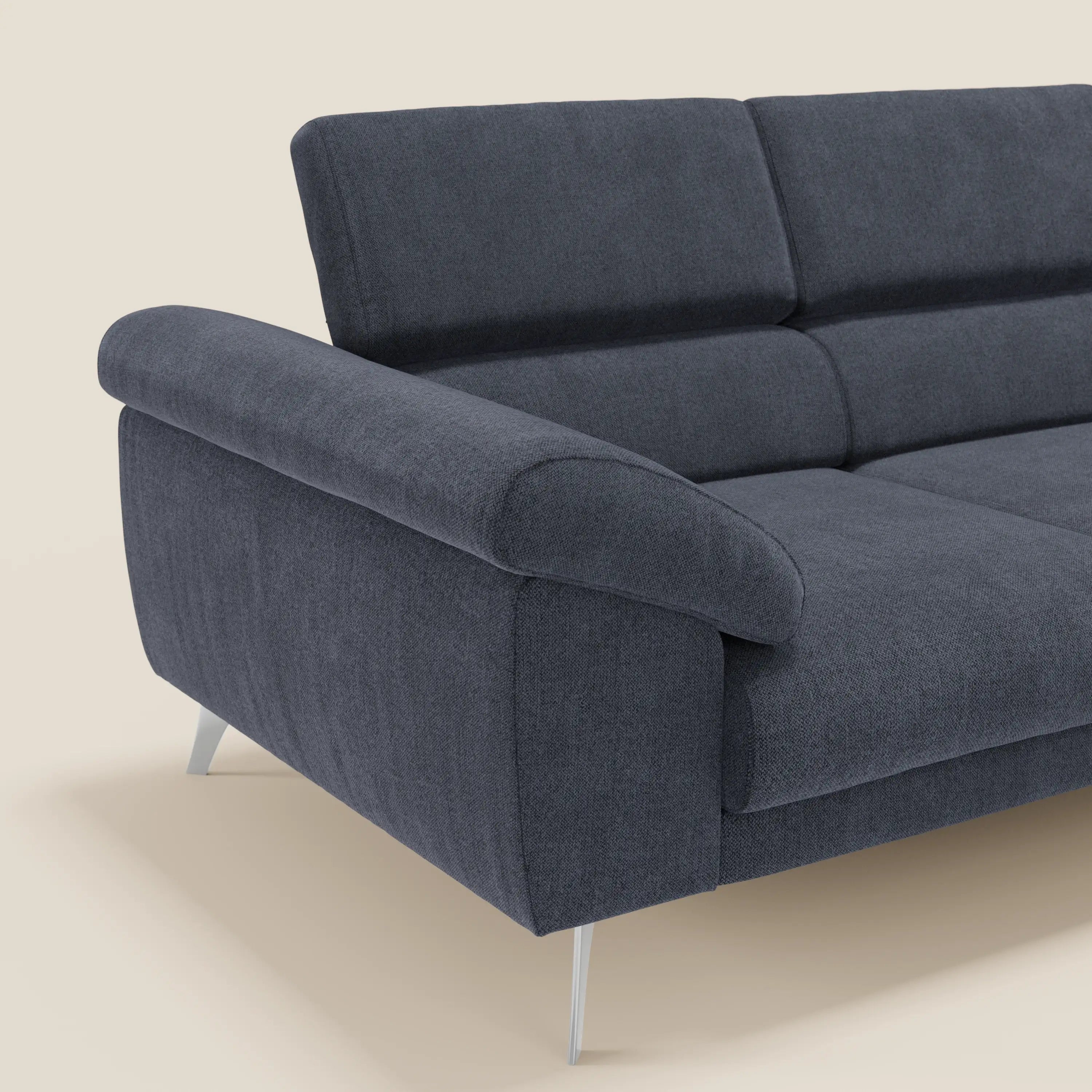 Il divano Donatello di Divani.Store in smacchiabile T23 blu ardesia è caratterizzato da 3 sedute allungabili, braccioli contenitore e poggiatesta reclinabili; mostrato in primo piano su sfondo beige per evidenziarne il design elegante e contemporaneo.